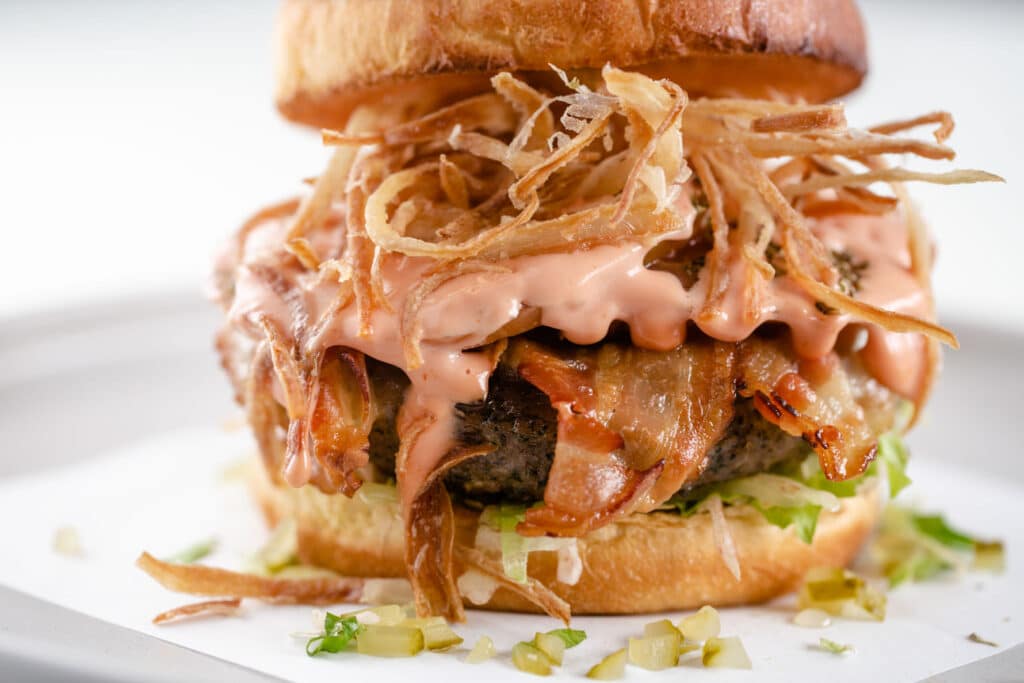 A loaded burger stacked high with bacon and onions