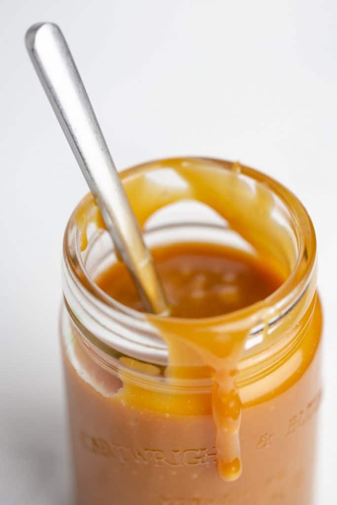 A spoon in a jar of salted caramel sauce