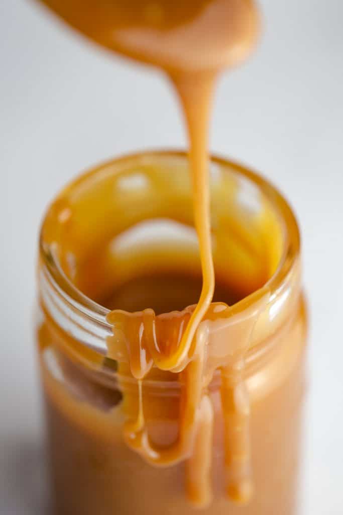 Salted caramel sauce being drizzled into a jar