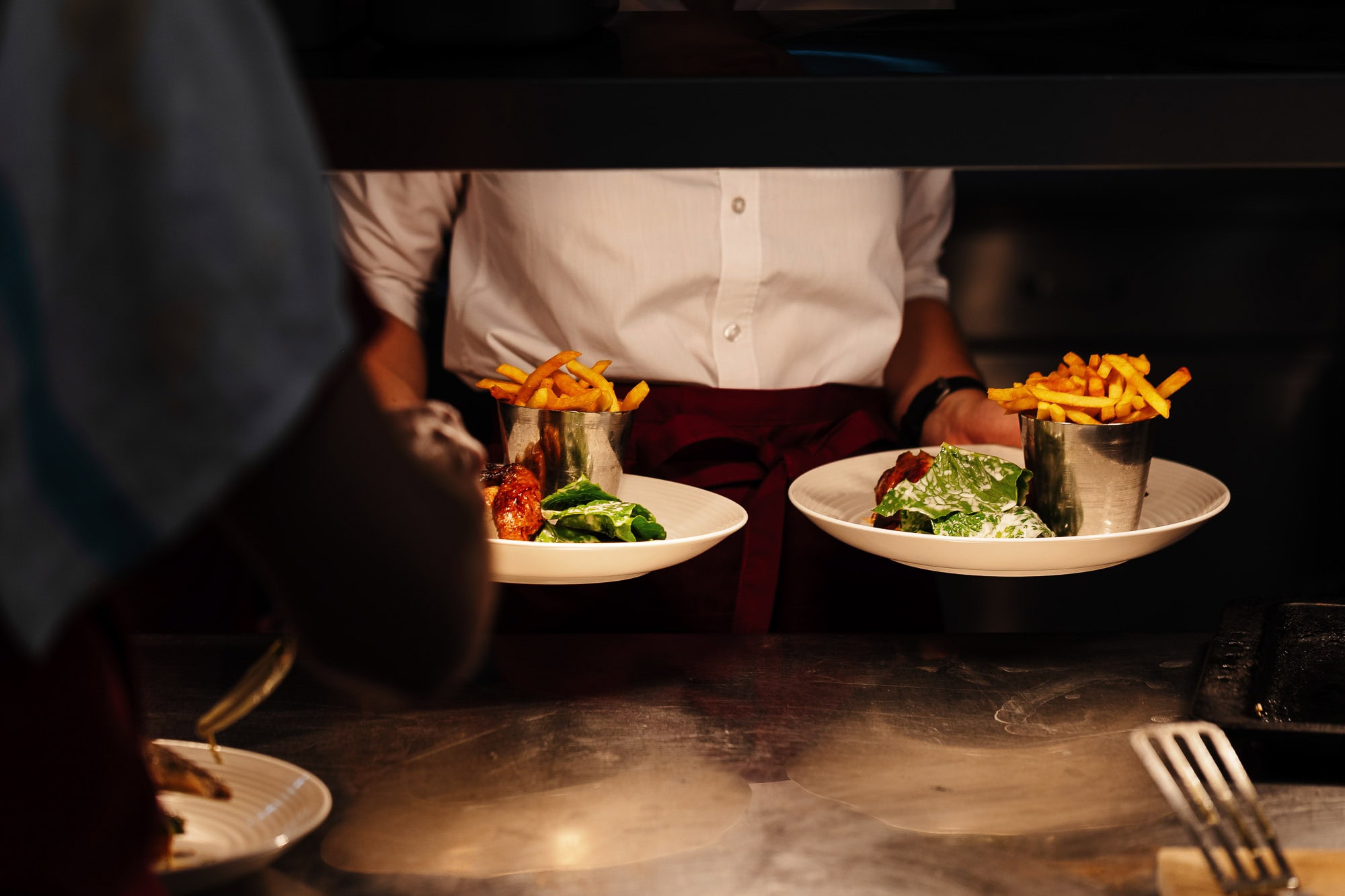 Culinary plating of gourmet dishes with French fries in a professional kitchen environment, showcasing food photography by Rutland Food Photographer.