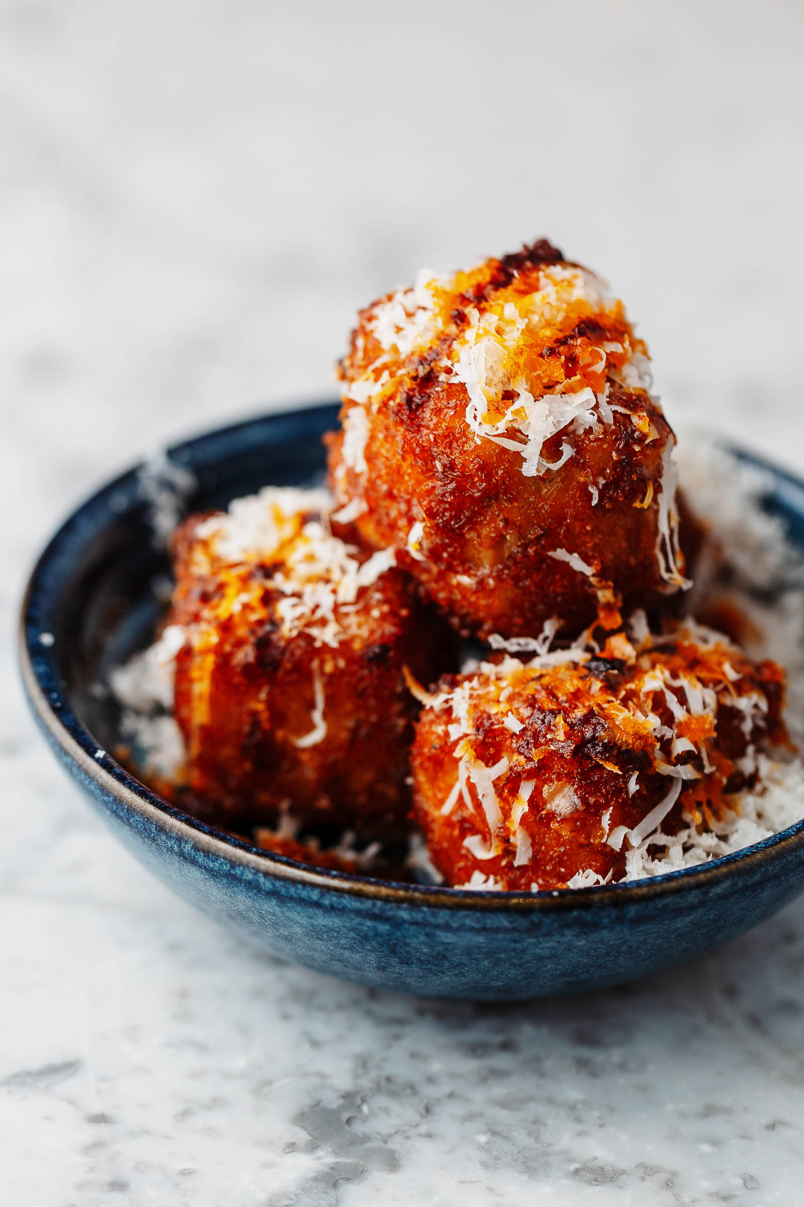 Three aranchini balls on a plate topped with parmesan