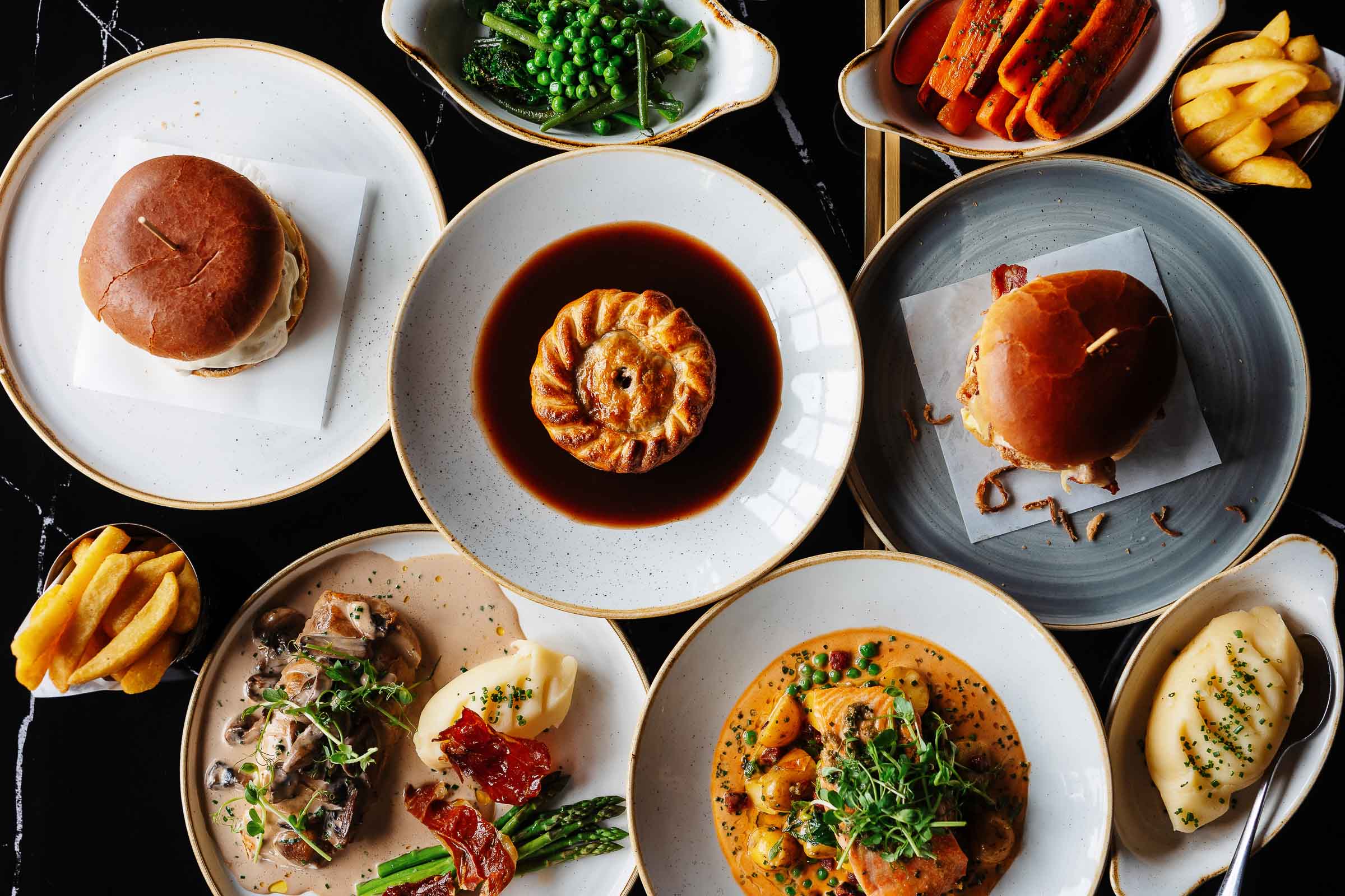 Delicious gourmet dishes including mini burgers, a warm pie in gravy, and seasonal vegetables, beautifully styled for food photography by Rutland Food Photographer.