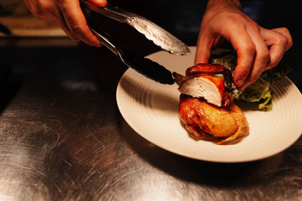 Succulent chicken being carved on a white plate, showcasing professional food photography by Rutland Food Photographer for clean plate.co.uk.