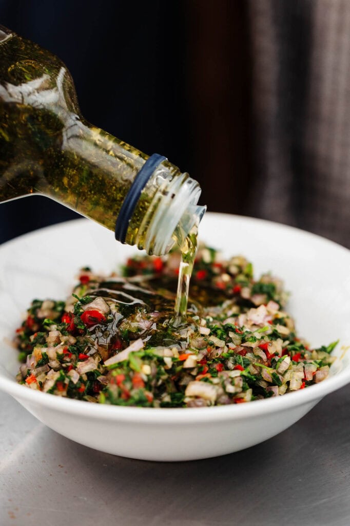 Fresh herb-infused oil being poured over a colourful chopped vegetable salad, showcasing professional food photography by Rutland Food Photographer for UK culinary and food styling clients.