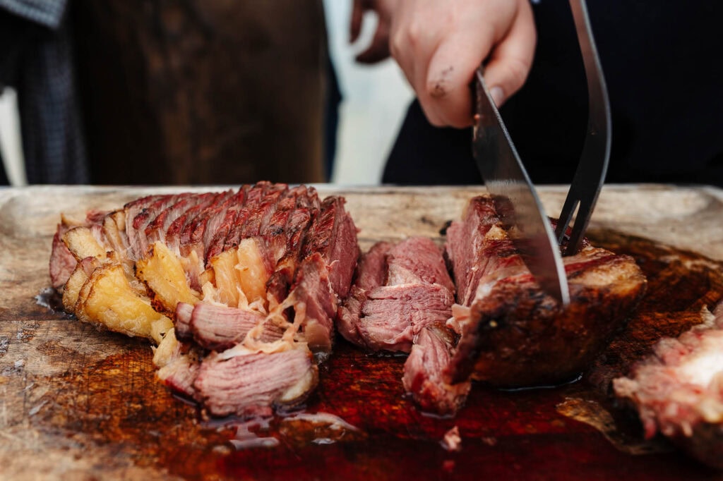 Juicy, perfectly cooked roast beef being sliced on a wooden cutting board by a professional food photographer in Rutland.