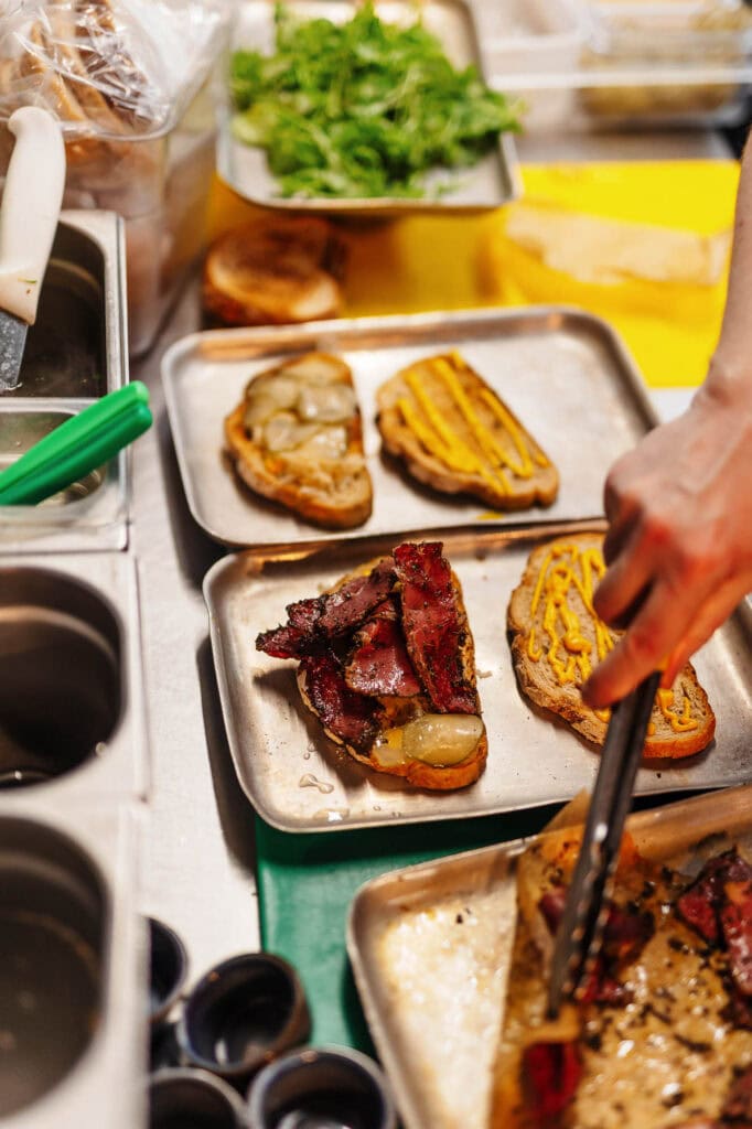 Delicious homemade open sandwiches with bacon, mustard, and onions on a catering tray, perfect for food photography and restaurant menu shots, focused on rustic British cuisine.