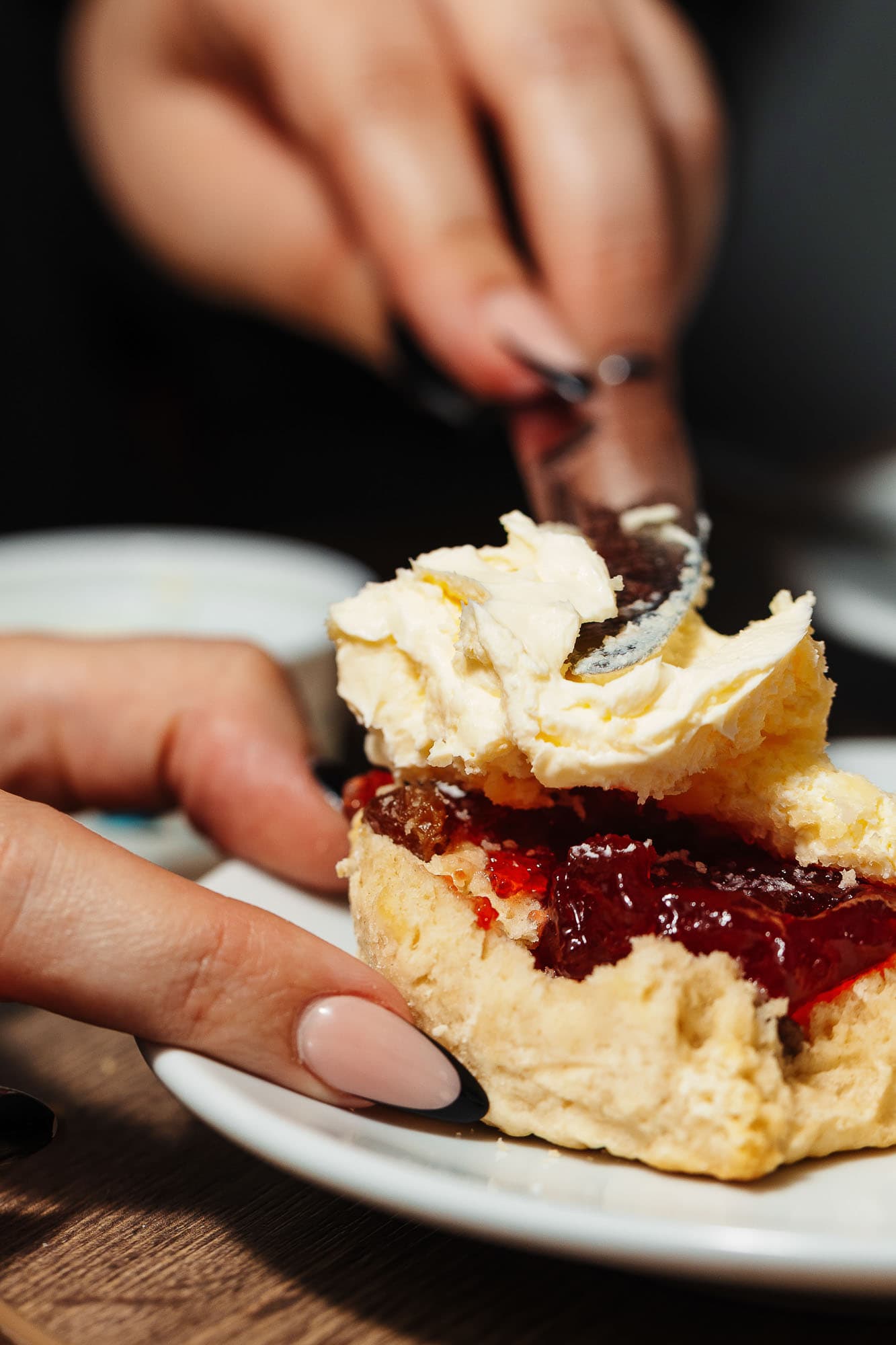 Golden flaky shortcrust pastry filled with vibrant berry jam, topped with creamy whipped cream, served on a white plate; delicious traditional British dessert, perfect for special occasions.