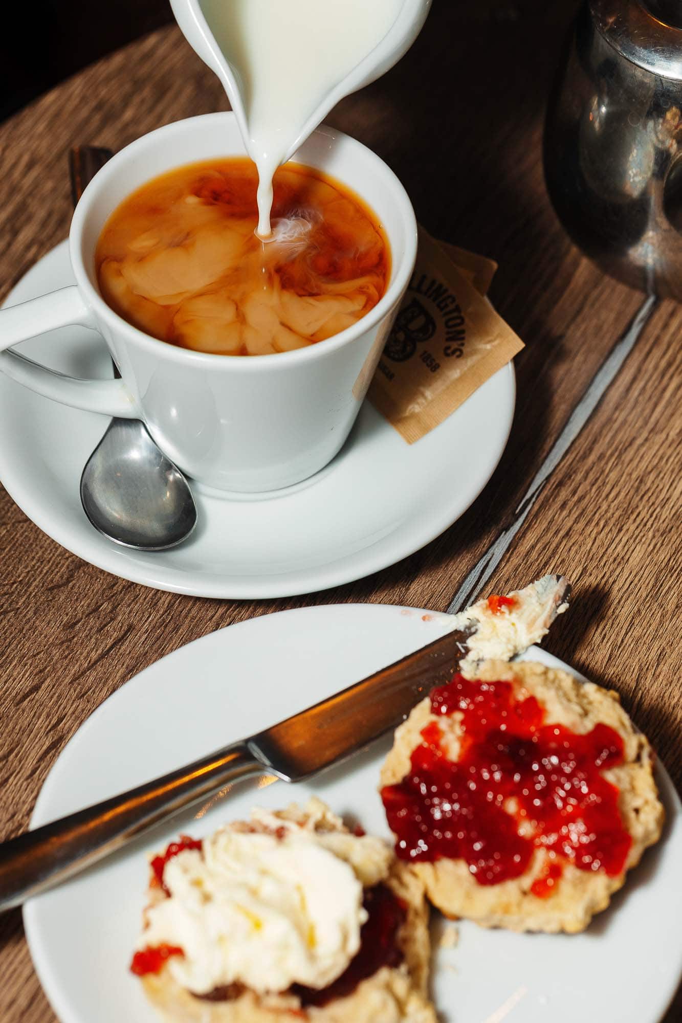Creamy milk being poured into a hot cup of tea, served on a rustic wooden table at a Rutland food photography location, showcasing classic British tea culture.
