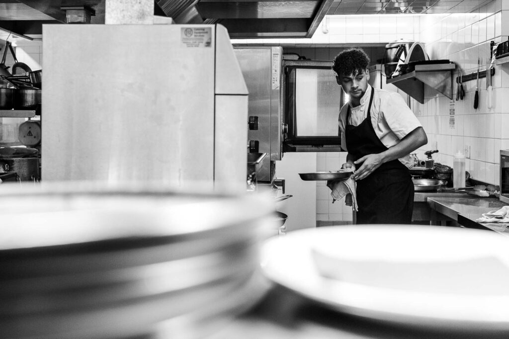 Creative food photography of a professional chef preparing dishes in a commercial kitchen, showcasing culinary expertise and attention to detail in food presentation.