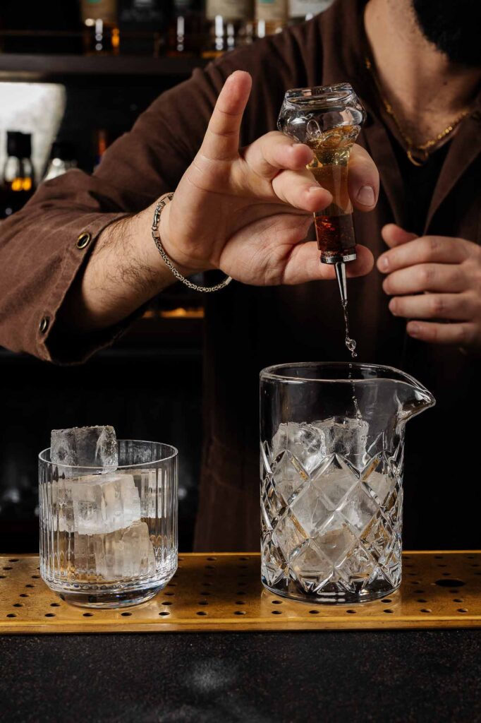 Cocktail photography London 1. Close-up of bartender pouring alcohol into a glass, showcasing professional mixology at a Rutland food and drink establishment.