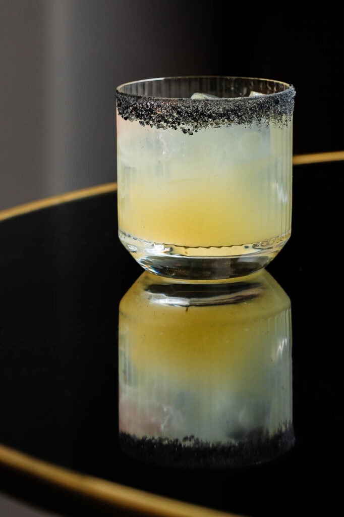 Vibrant cocktail with black salt rim on a reflective black surface, expertly captured by Rutland food photographer for stylish food and beverage presentation.