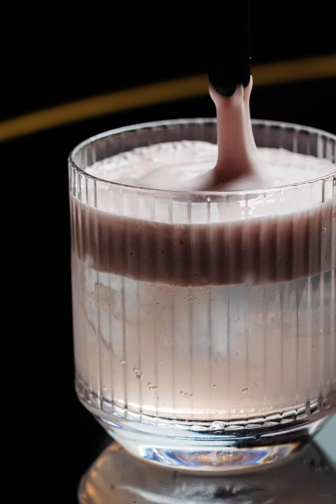 Rich, creamy chocolate milkshake being poured into a vintage glass with a ribbed design, highlighting indulgent dessert photography in Rutland by professional food photographer.