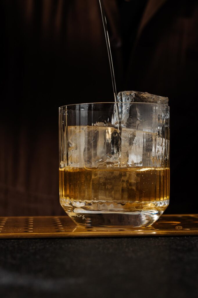 1. Close-up of a whisky on the rocks in a glass with pouring water, shot by Rutland food photographer.
