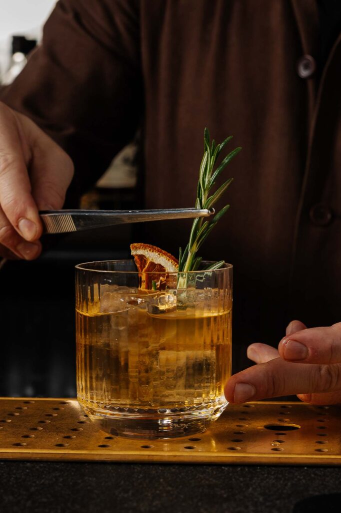 Aromatic cocktail garnished with a sprig of rosemary and dried citrus slice, taken by Rutland food photographer for appealing food and drink imagery.