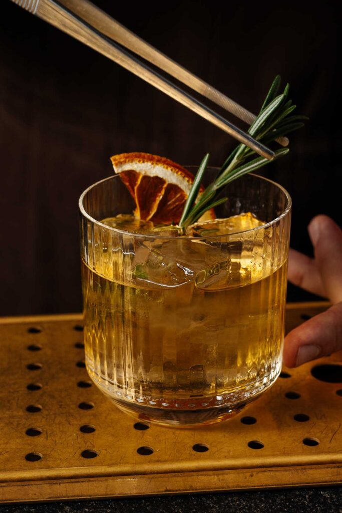 Fresh whisky cocktail garnished with orange slice and rosemary, perfect for premium food photography in Rutland.