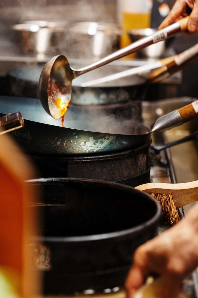 Chef cooking with a pan over a stove, emphasizing professional food photography and culinary artistry.