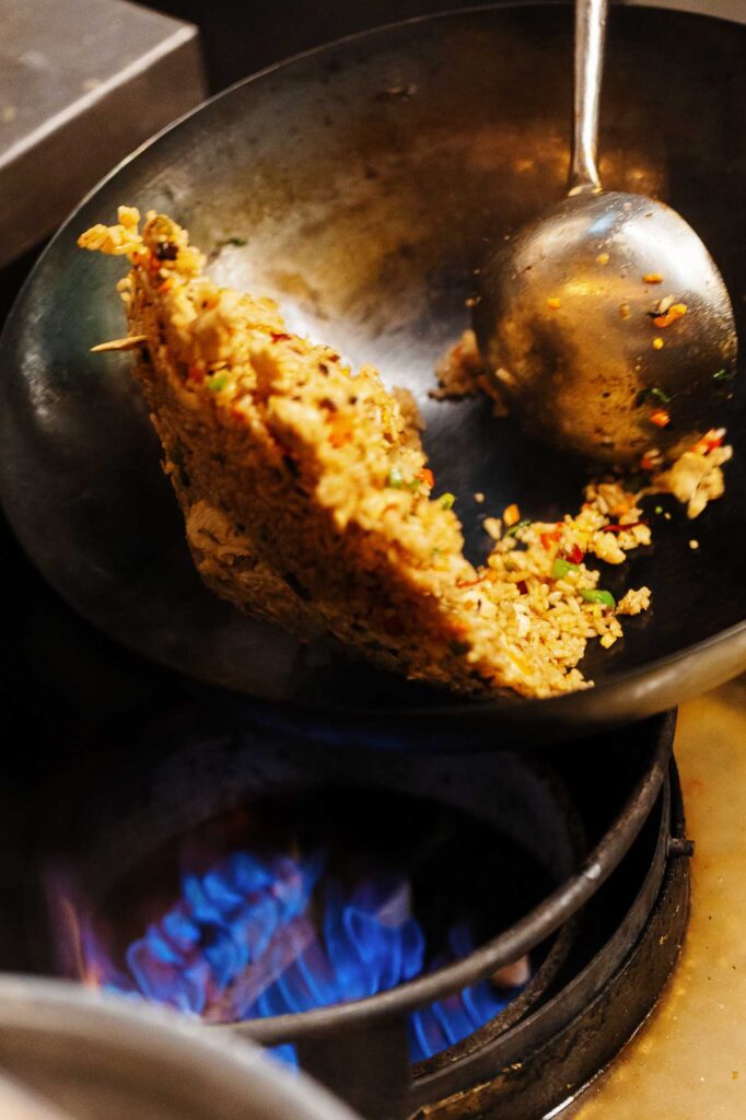 Fried rice in a wok with a metal spatula, captured by a Rutland food photographer, highlighting the texture and colour of the dish.