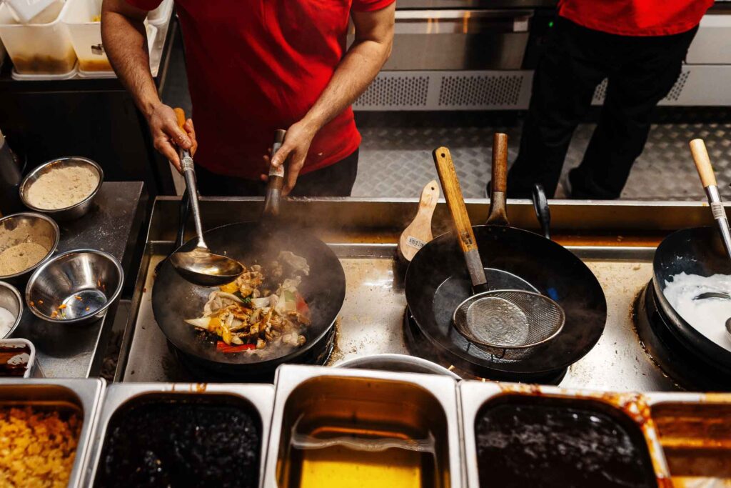 A chef expertly prepares a colourful stir-fry in a professional kitchen, showcasing fresh vegetables and sizzling ingredients in a wok.