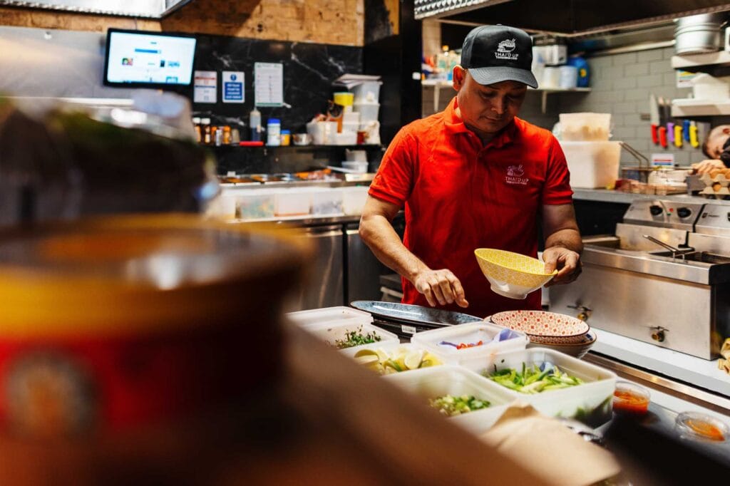 Chef preparing food in a commercial kitchen, focusing on fresh ingredients and food presentation.