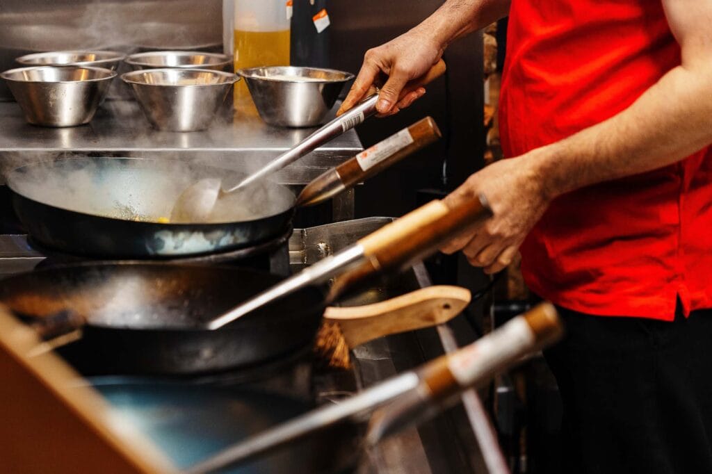 Skilled chef cooking with a frying pan in a professional kitchen, showcasing culinary expertise and food preparation for food photography.