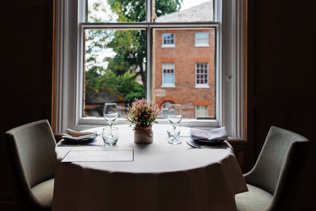 Stylish restaurant table set for two with wine glasses, cutlery, and a floral centrepiece, captured by Rutland food photographer.