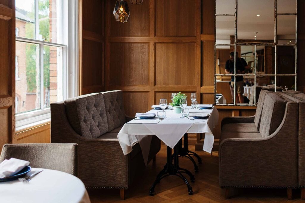 Elegant restaurant interior with a table set for dining, featuring white tablecloths, glassware, and floral centrepieces, perfect for capturing professional food photography in Rutland.