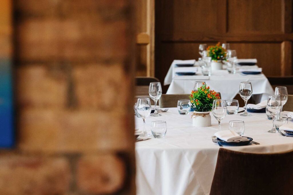 An image of a beautifully arranged dining table in a restaurant, featuring white tablecloths, floral centrepieces, wine glasses, and neatly set cutlery, perfect for special occasions.