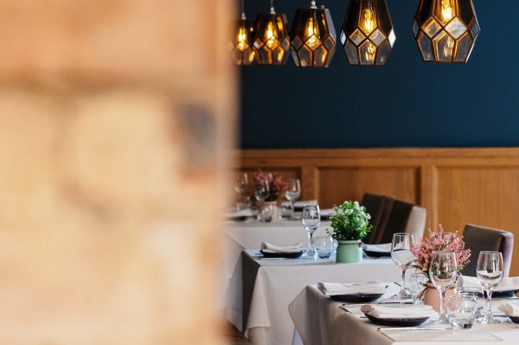 Modern restaurant dining area with beautifully arranged tables, glassware, and floral centrepieces, perfect for showcasing high-quality food photography.