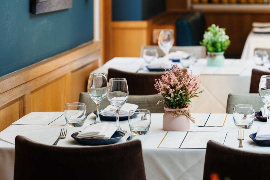 Elegant restaurant table with wine glasses, water glasses, cutlery, and a floral centrepiece, perfect for fine dining in Rutland.