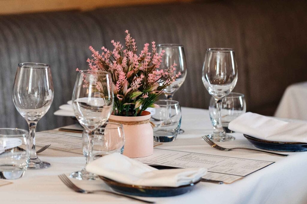 Stylish table arrangement featuring wine glasses, water glasses, and a pink floral centrepiece, perfect for upscale restaurants or special events in Rutland.