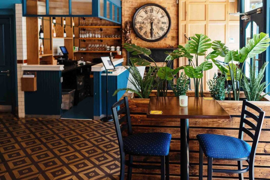 Stylish restaurant interior featuring wooden furniture, green potted plants, and a cozy atmosphere, ideal for dining and socialising.
