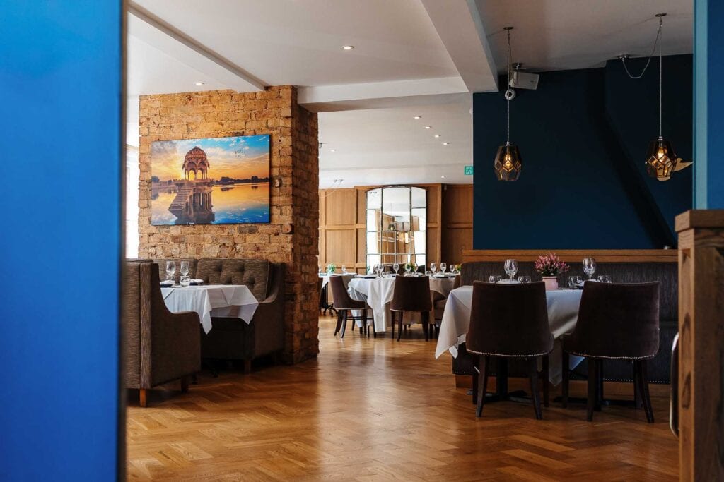 Modern restaurant interior with stylish decor, wooden flooring, and neatly arranged tables with white tablecloths, perfect for fine dining experiences in Rutland.