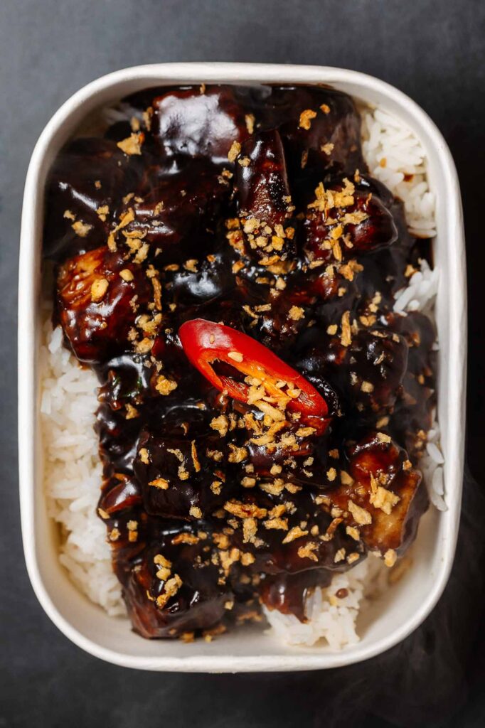 Inspired beef stew topped with crispy garlic and red chili slices, served over fluffy white rice in a white bowl. Perfect for comforting, flavourful meals.
