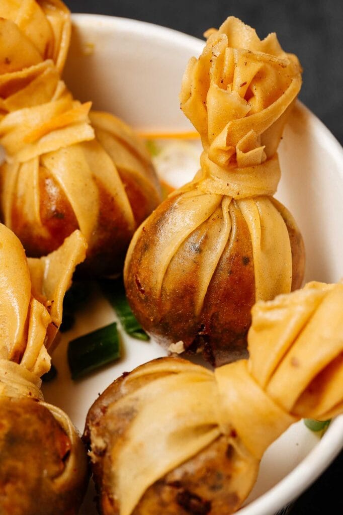 Close-up of mini beef wellingtons wrapped in pastry, served in a white bowl, showcasing golden-brown pastry and tender beef, perfect for gourmet food photography.