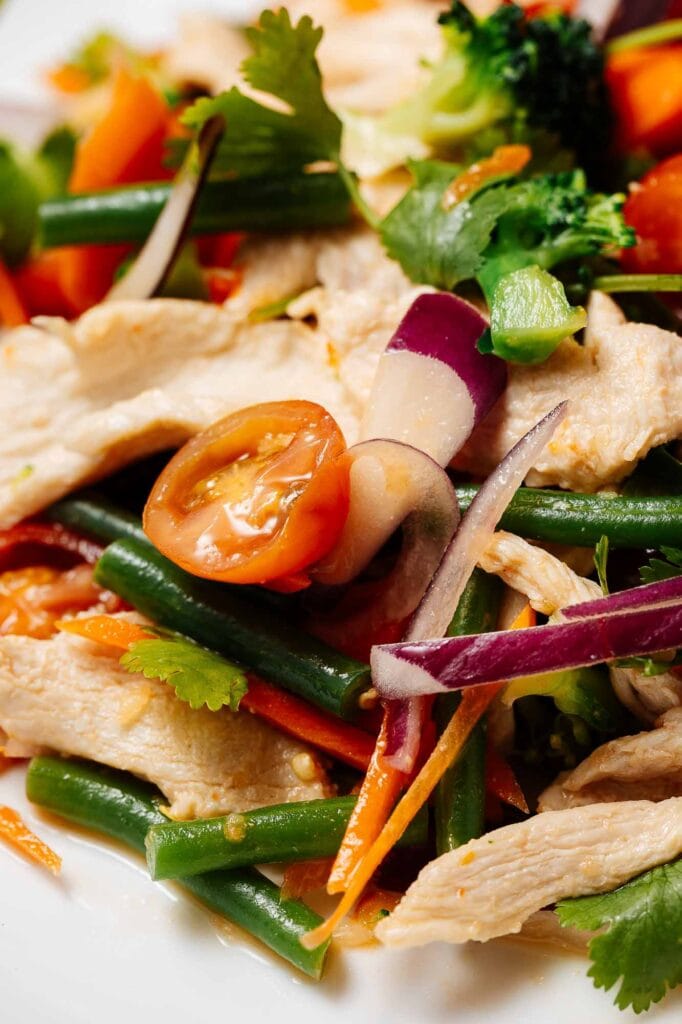 A vibrant chicken and vegetable salad featuring cherry tomatoes, green beans, radishes, and fresh herbs, showcasing colourful, healthy, and appetising food photography.