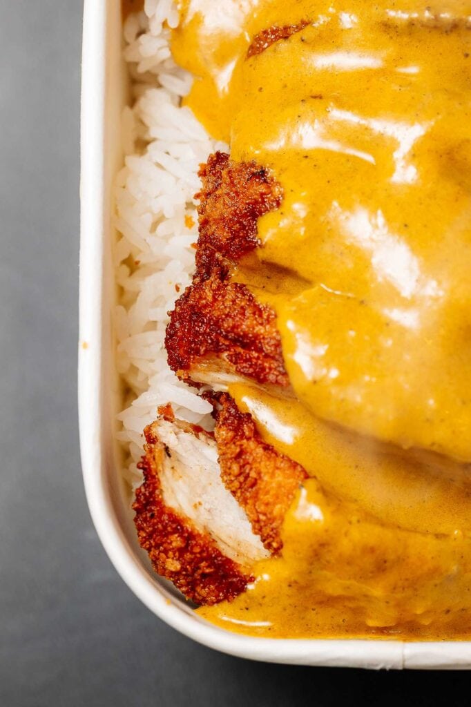 Chicken Katsu Curry with rice in a takeaway box, close-up.