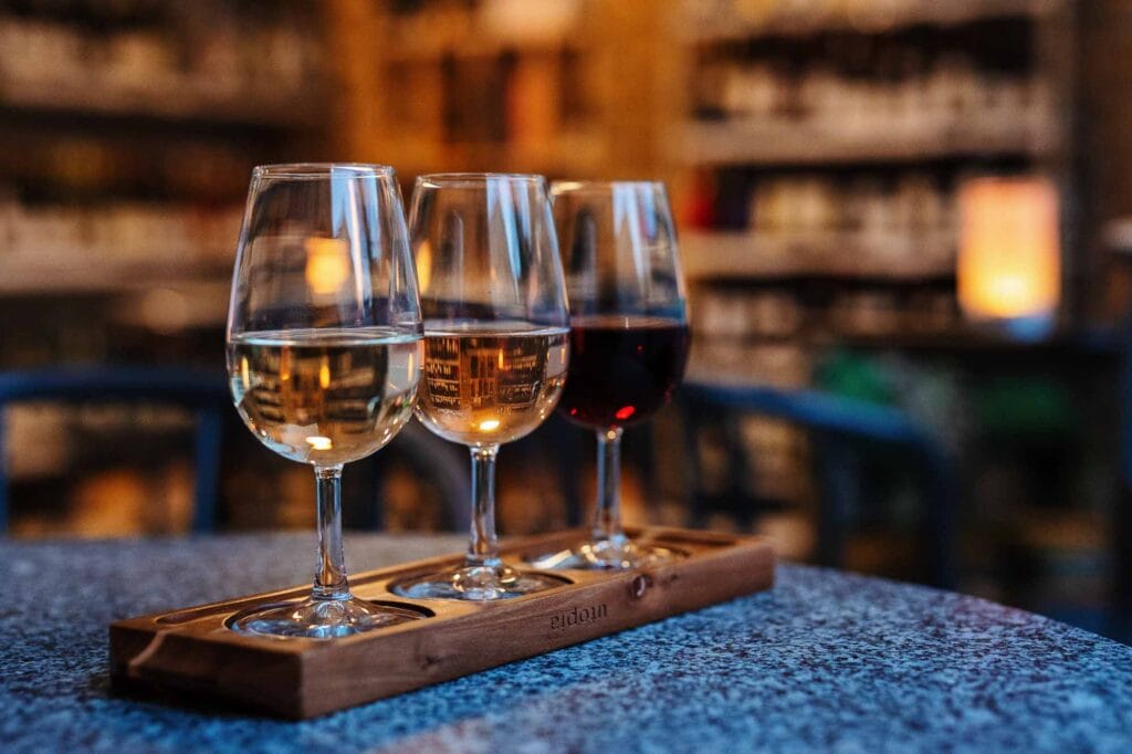 Three glasses of white, rosé, and red wine on a tasting tray in a cosy Rutland restaurant, showcasing local wine selection and elegant presentation.