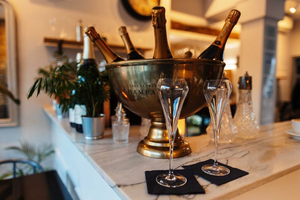 Elegant champagne bottles chilling in a silver ice bucket at a stylish event, with two empty champagne flutes ready for serving. Perfect for celebrating special occasions or upscale gatherings.