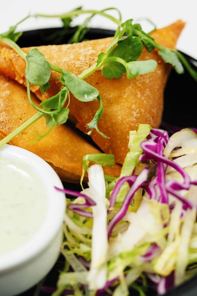 Golden fried samosas served with fresh cabbage slaw and mint chutney, perfect for Indian restaurant dining in Oakham.