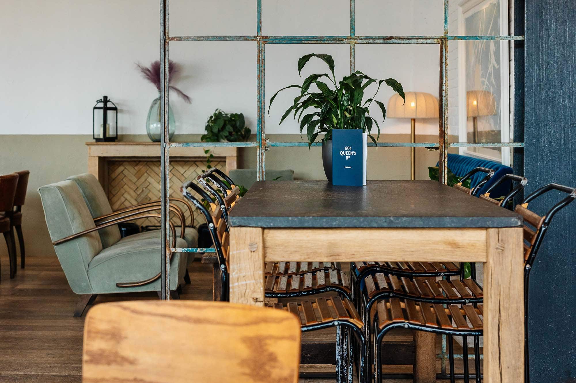 Stylish dining space featuring a large wooden table, contemporary chairs, and decorative plants in a bright, inviting restaurant setting.