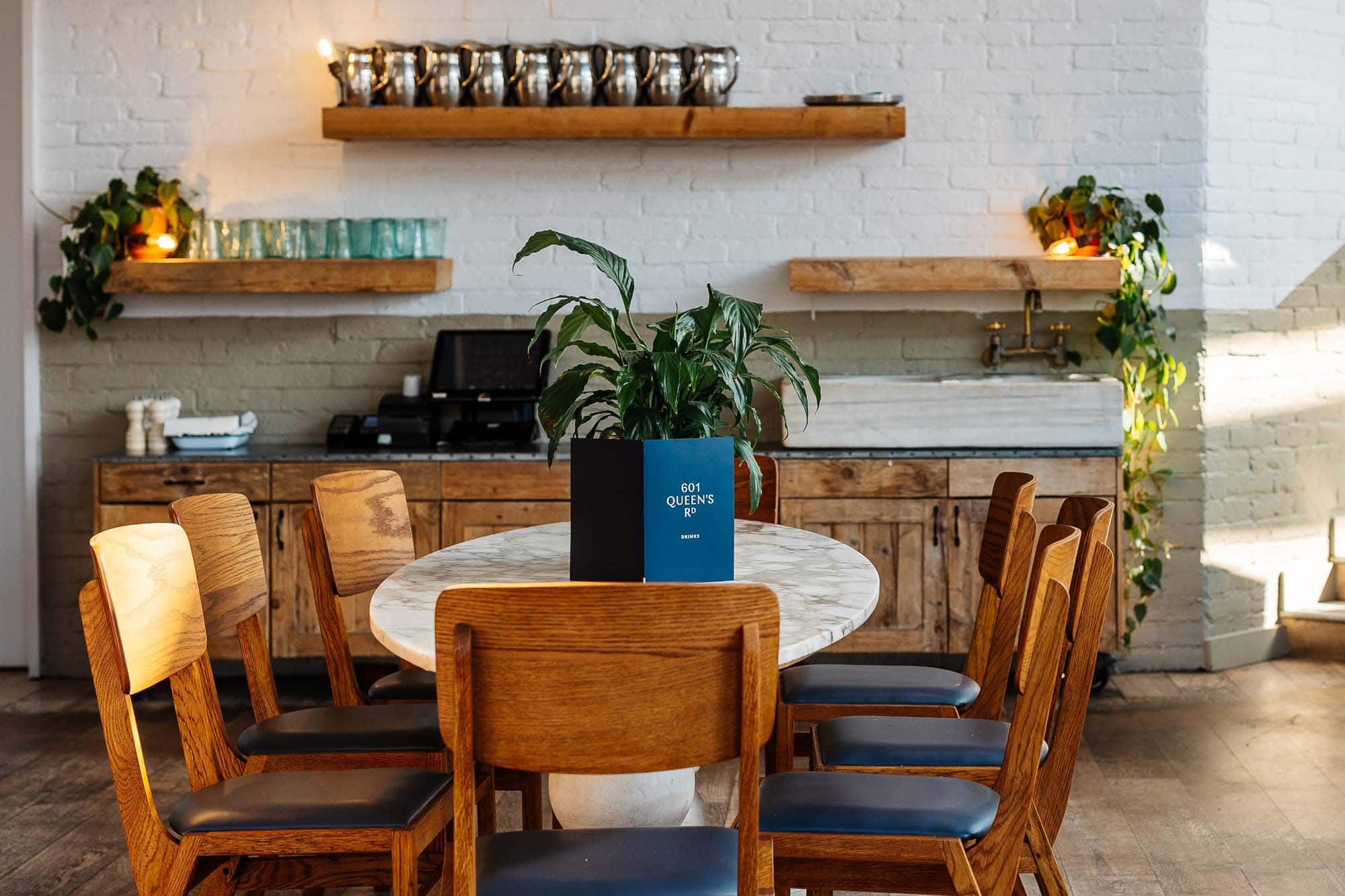 Stylish dining space featuring a round table, wooden chairs, and minimalist decor in a bright, contemporary setting. Perfect for food photography and restaurant branding.