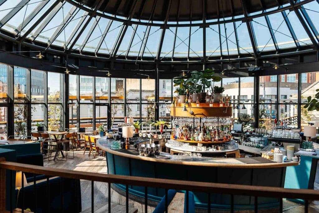 Indoor bar with a curved counter, stylish seating, and large glass windows showcasing city views, captured by a professional food photographer in Rutland.