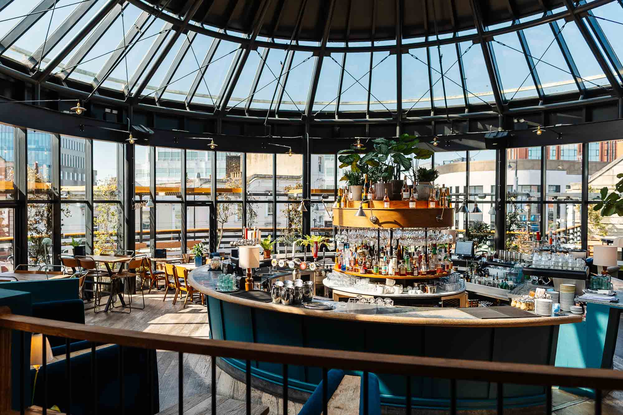 Indoor bar with a curved counter, stylish seating, and large glass windows showcasing city views, captured by a professional food photographer in Rutland.