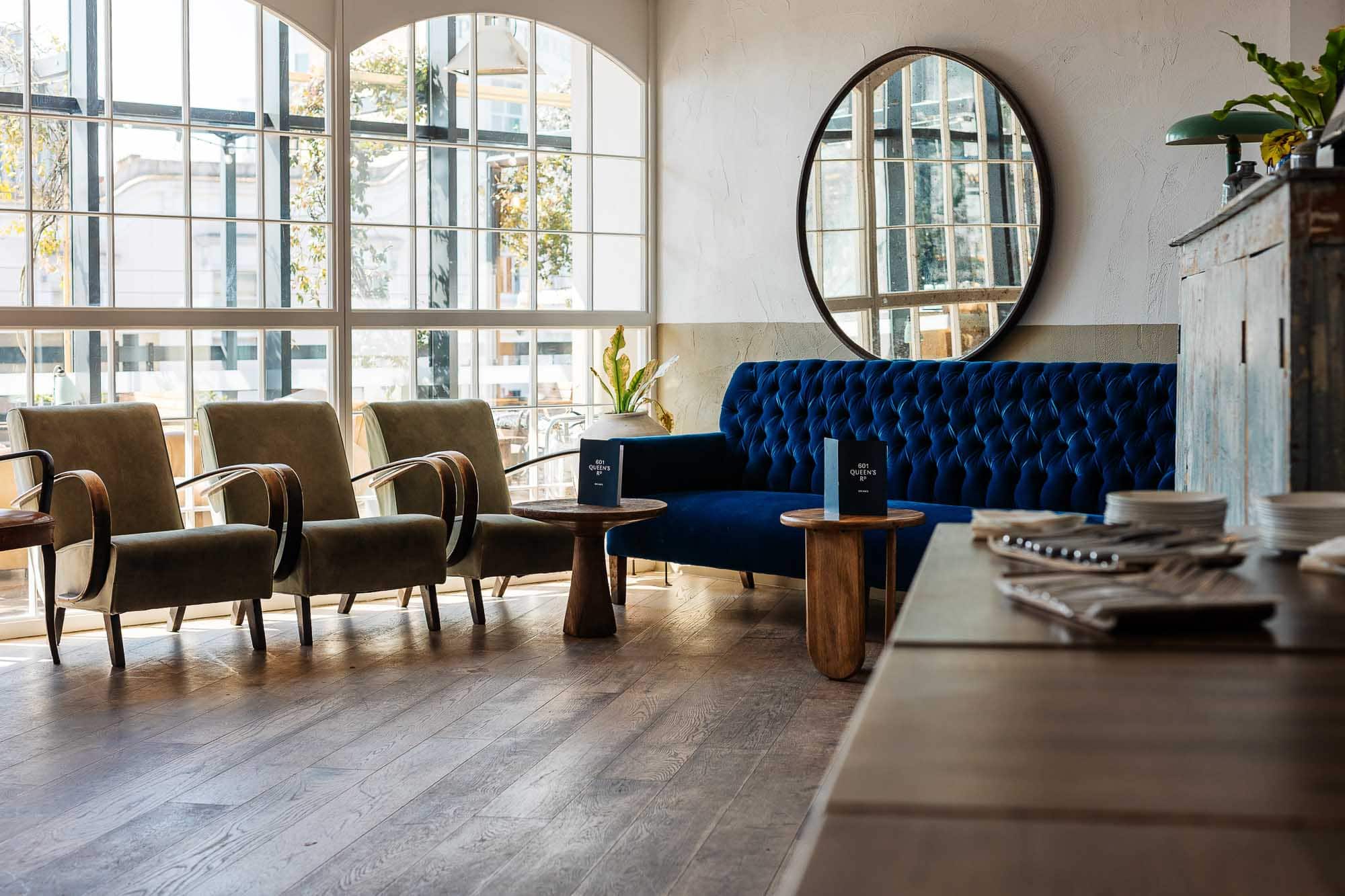 Stylish lounge area with large windows, velvet sofa, and vintage chairs, perfect for relaxing or casual meetings in a contemporary setting.
