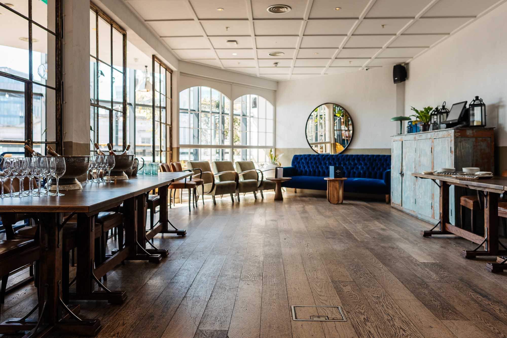Bright and airy restaurant interior with large windows, wooden flooring, and stylish seating arrangements, perfect for food photography and capturing inviting dining atmospheres.