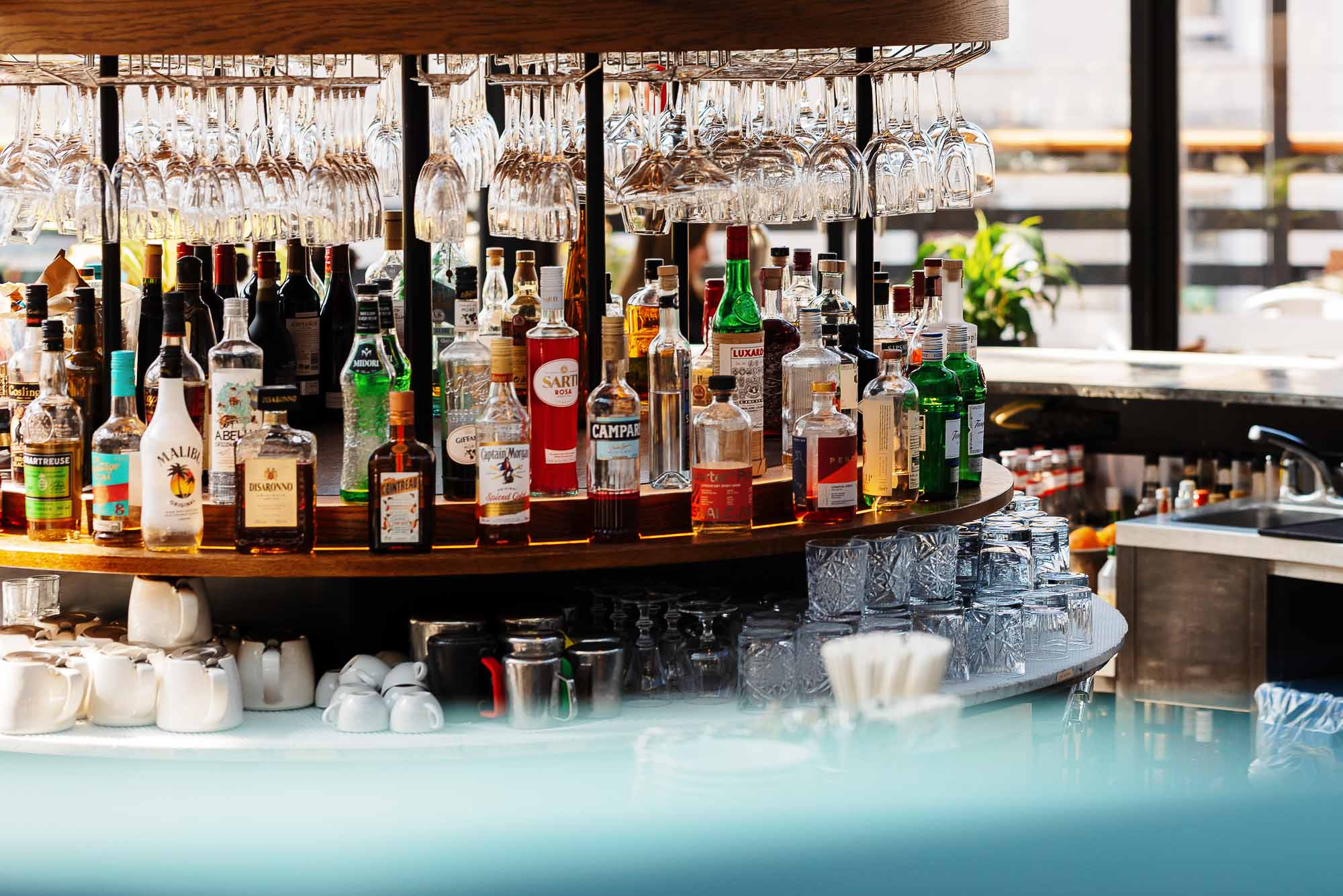 A vibrant bar scene featuring a variety of liquor bottles, wine glasses, and cocktail tools, captured by Rutland food photographer to showcase the lively atmosphere of a modern bar setting.