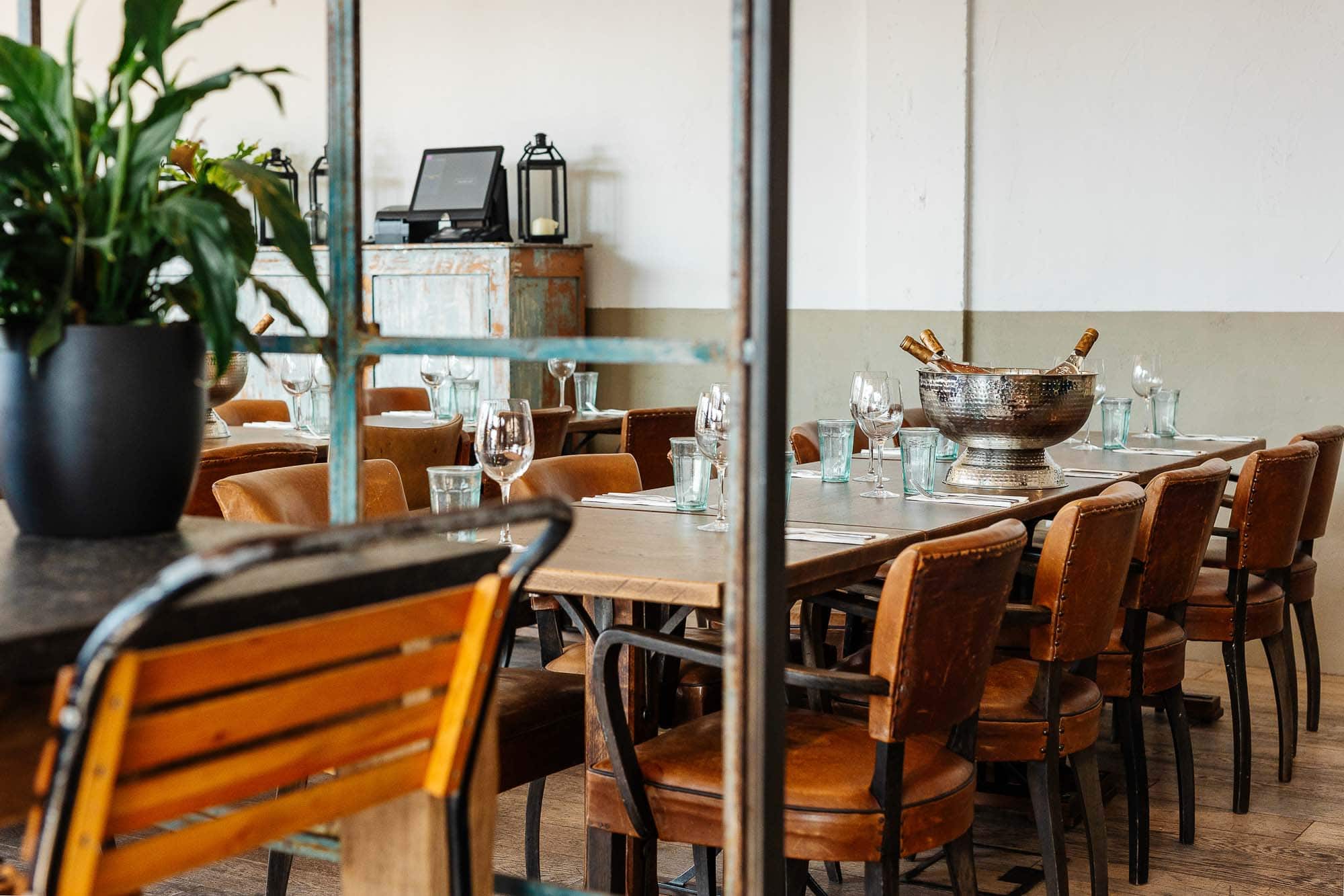 Elegant restaurant dining area with wooden tables, leather chairs, and glassware, featuring a modern yet cozy atmosphere perfect for dining experiences.